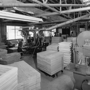 An antique image of a Fetzer Architectural Woodworking employee working with a machine.